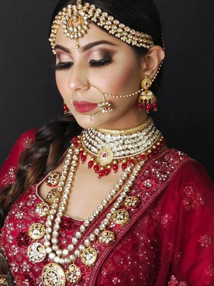 A bride wearing a layered pearl and Kundan set with red accents. The combination of pearls and red beads creates a soft yet traditional look.