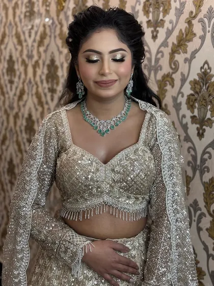 A stunning engagement look featuring a sequined golden lehenga. The makeup is all about shimmer, with a golden cut-crease eye and a glossy nude lip.