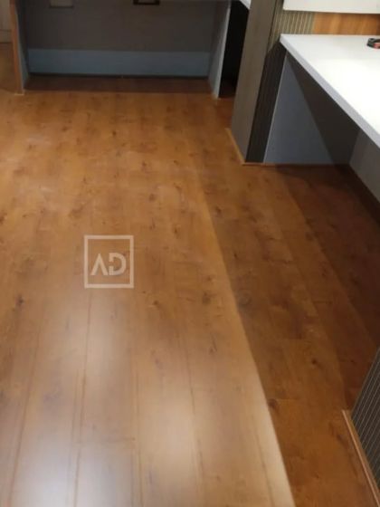 Here is a wood-look floor in a commercial office space, installed around workstations. This flooring is designed to handle the daily wear and tear of office chairs and foot traffic while maintaining its polished look.