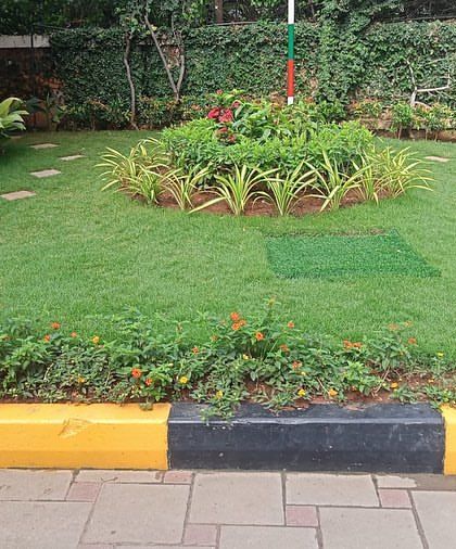 The completed central landscaping feature at Sobha Carnation, with a circular plant bed and stepping stones on the lawn.