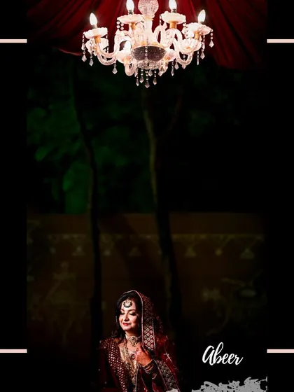 A creative portrait of the bride, framed to emphasize the elegance of the venue and her stunning red wedding attire. The chandelier adds a touch of grandeur to this artistic shot.