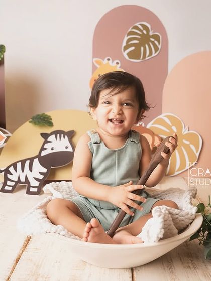 A big, gummy smile from the birthday boy, sitting in a white bowl amidst his jungle friends.