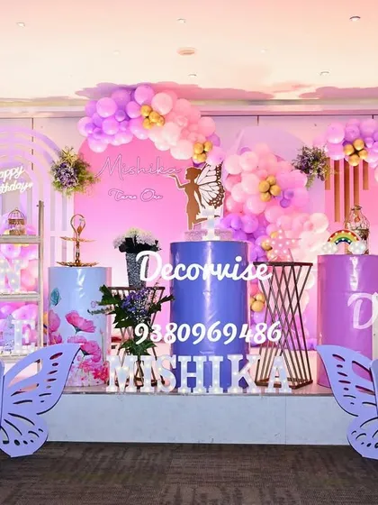 We create magical, fully-realized party themes like this enchanting butterfly wonderland for Mishika's first birthday. This grand stage setup features large butterfly wing cutouts, personalized marquee letters, a custom backdrop with a neon sign, and coordinated balloon garlands, all designed to create a perfect photo opportunity.