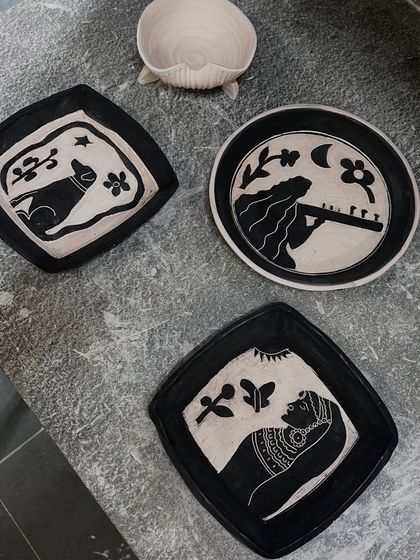 The complete set of three commissioned wall plates, telling a story through hand-carved illustrations. This set captures a love for dogs, music, and acting, creating a unique piece of personalized ceramic art for the home.
