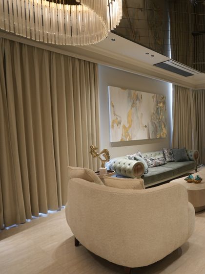 This angle shows the relationship between the dramatic chandelier, the floor-to-ceiling curtains, and the seating area, all working together to create a cohesive and luxurious space.
