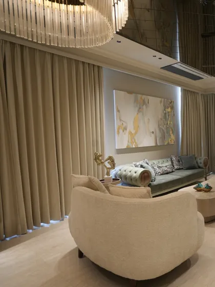 This angle shows the relationship between the dramatic chandelier, the floor-to-ceiling curtains, and the seating area, all working together to create a cohesive and luxurious space.