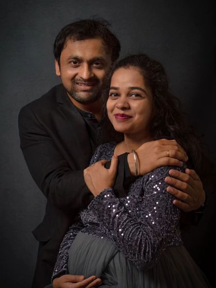 An elegant couple's portrait showing the partner's gentle embrace. This pose is a beautiful way to show support and love during the pregnancy journey.