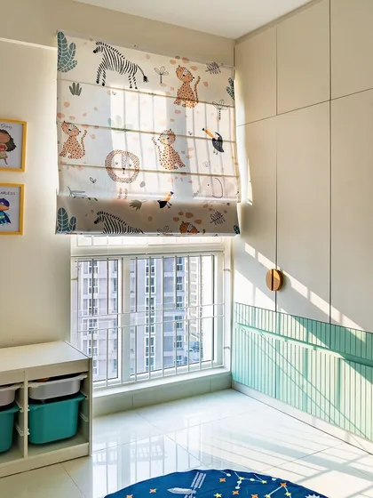 The playful details in this kids' room include animal-themed roman blinds and a two-tone wardrobe with mint green fluted panels. The space is bright, cheerful, and full of character.