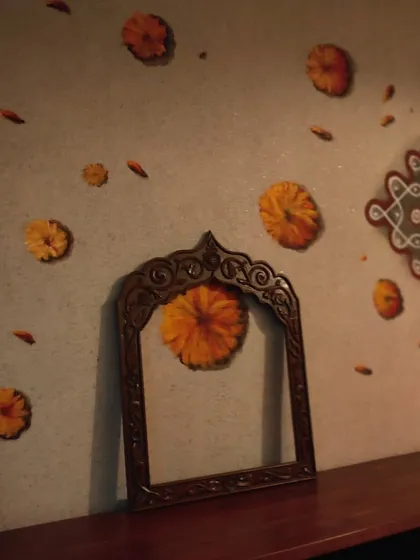An angled shot of the traditional kolam and marigold mural, showing how it wraps around a corner and integrates with the room's furniture. This demonstrates how I design wall art to complement the existing architecture and interior decor of a home.