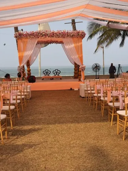 This wide shot shows the complete setup for a peach-themed lawn wedding by the sea. We arranged the guest seating to provide a clear view of the elegantly draped mandap and the ocean beyond.