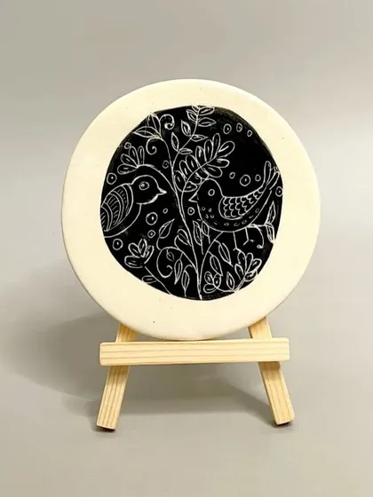 This beautifully hand-painted ceramic tile, featuring a sgraffito bird design, is a stylish and unique way to jazz up your home decor. It's a perfect addition to a bookshelf or side table.