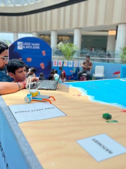 An instructor helps a young participant with his robot at our "Guardians of the Ocean" event at Forum Mall, showing how we make learning interactive and engaging for everyone.