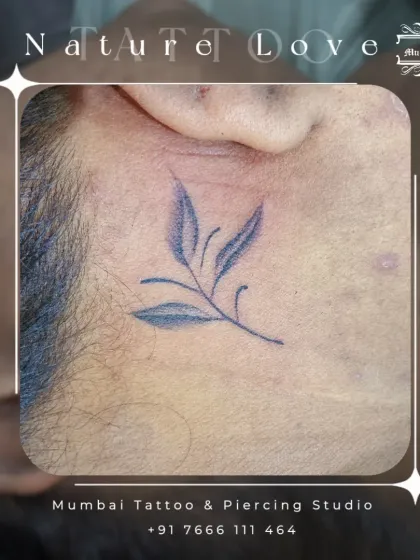 A tiny leaf branch tattoo placed discreetly behind the ear. This is a great example of our fine line nature tattoos, perfect for anyone wanting a subtle connection to the natural world.