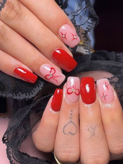 The color of the season. This cute set combines bold red nails with a sheer pink base, featuring hand-painted red bows and sparkling star accents.