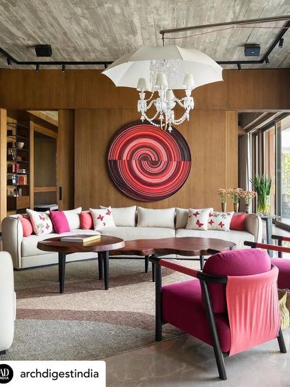 A playful and vibrant lounge in the K Residence, where a whimsical umbrella chandelier hangs over a bold, circular artwork. The fuchsia armchairs and butterfly cushions add pops of colour, creating a space that is full of life and personality, perfect for casual family gatherings.