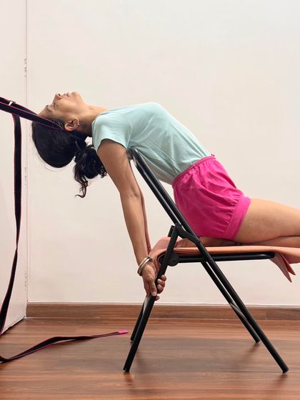 Here, I demonstrate a supported backbend on a chair with a belt for traction. This setup opens the chest and lengthens the spine, preparing the body for pranayama. It is a technique for generating cosmic vital energy by fusing the elements of fire (mind) and water (body).