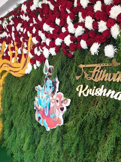 The Krishna-themed backdrop for a naming ceremony, featuring a tree cutout and a custom nameplate.