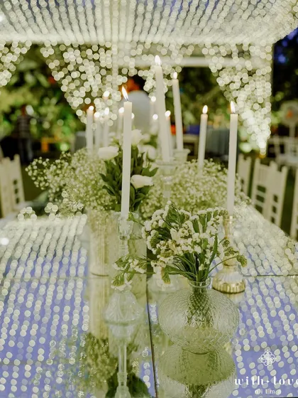 The reflection of fairy lights on a mirrored table, with tall candles and baby's breath adding to the ethereal feel. We use light and reflection to create a sense of infinite space and magic.