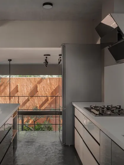 The kitchen is situated on a level above the car park, a design choice that allows it to remain connected to the main living volume and garden views. This galley-style kitchen is efficient and modern, with sleek cabinets and an open view.