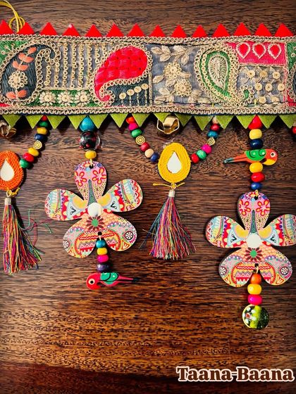 A close-up of the asymmetrical details in the 'Taana Baana' toran, with its hand-painted flowers and colorful tassels.