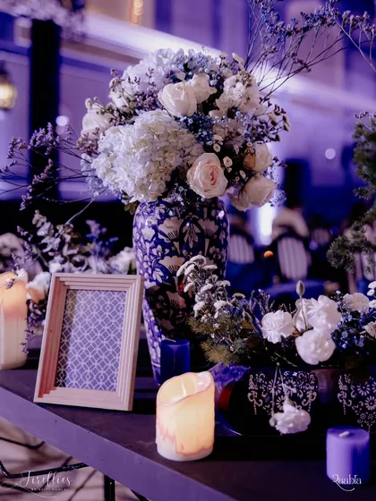 A floral arrangement in a blue and white ceramic vase, reflecting the pottery theme of the Sangeet. The soft white and blue flowers complemented the dramatic lighting of the event.