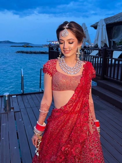 The bride in her red Tarun Tahiliani lehenga, her romantic updo perfect for a wedding by the sea.