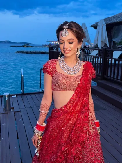 The bride in her red Tarun Tahiliani lehenga, her romantic updo perfect for a wedding by the sea.