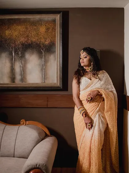 An artistic shot of our bride during her Haldi ceremony. The warm tones of the decor complement her beautiful, glowing makeup.