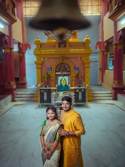 A creative shot of a South Indian couple in a temple, with the large temple bell blurred in the foreground. This adds a dynamic element and sense of place to the portrait.