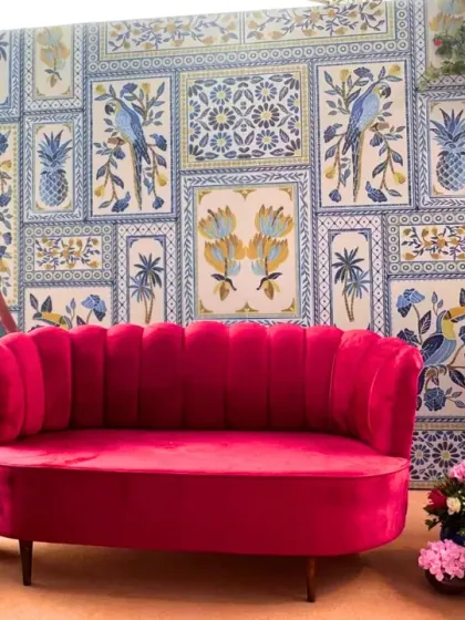A fun and quirky photo booth featuring a custom illustration of the couple. The backdrop of blue and white tiles and a bright pink sofa makes for a vibrant and personalized spot.