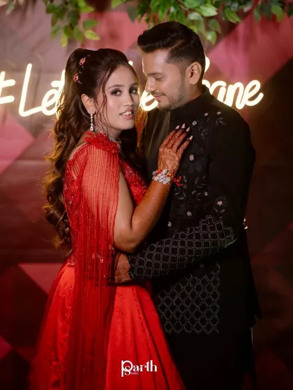 The couple posing in front of a neon sign, looking glamorous and ready to party.