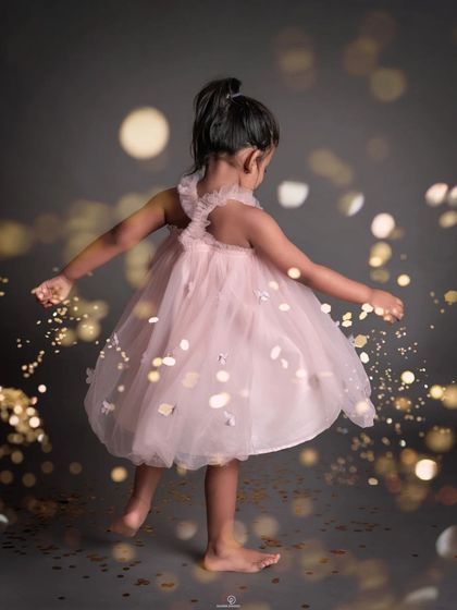 A magical series of a little girl in a pink dress playing with golden glitter. These photos capture her pure joy and the whimsical movement of the sparkling confetti.