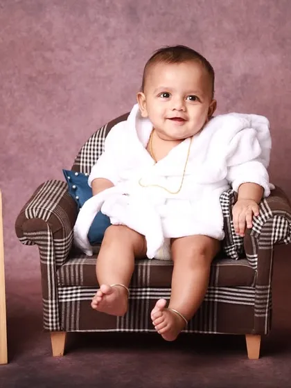 Celebrating the half-birthday milestone with a fun and quirky studio session. This little one is styled in a comfy robe on a miniature armchair, marking six months of growth and giggles.