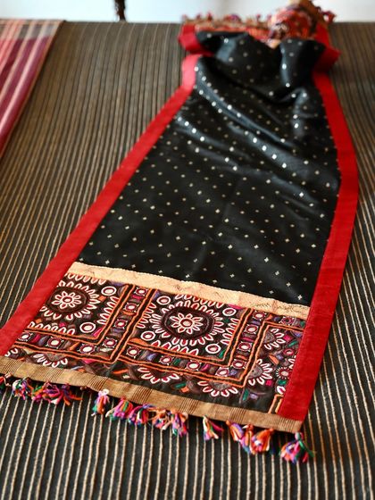 This reversible runner features a black and white polka-dot silk on one side and a rich red on the other. It is anchored by a panel of vintage Kutch embroidery.