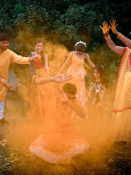 The vibrant energy of a Gujarati Haldi ceremony. This action shot, with turmeric powder filling the air, captures the fun and playful spirit of the celebration.