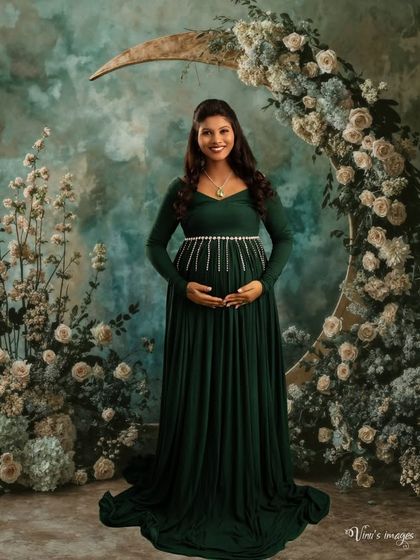A beautiful portrait set against a crescent moon floral arrangement. The dark green gown and the dreamy backdrop create a magical, celestial vibe.