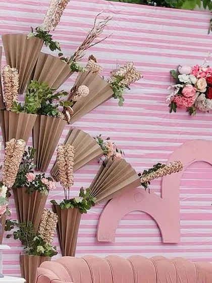 A close-up of the unique stage backdrop, which combines dried palm fans and fresh flowers in artistic head-shaped vases for a truly creative statement.