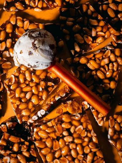 A creative flatlay featuring ice cream on a bed of chikki (peanut brittle). The textures and colors create a visually interesting composition that's both artistic and appetizing.