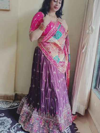 A client looking lovely in a purple and pink lehenga with a colorful bandhani dupatta, perfect for a festive look.