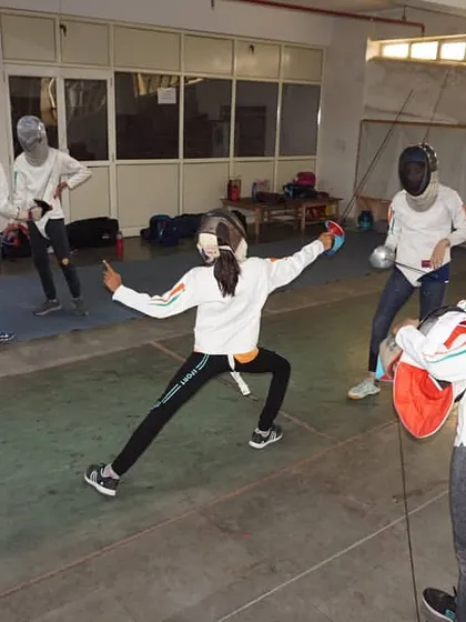 A student practices her lunge towards a partner during a footwork drill. This helps fencers gauge distance and timing for their attacks.