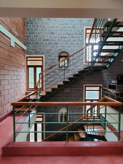 A multi-story view of an interior, showing how exposed brick, stone, and red oxide flooring are used consistently across different levels.