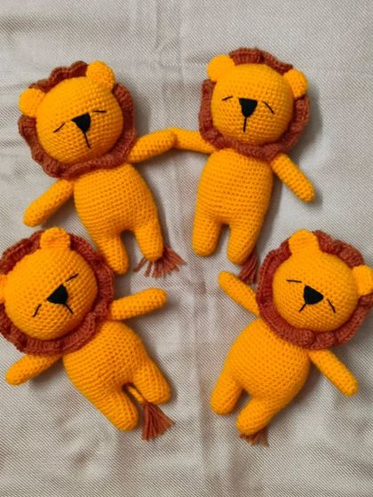 A group of four small, handmade crochet lions. They are so cute and perfect for playing jungle games.