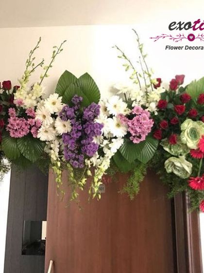 A colorful and vibrant door decoration. This arrangement features a mix of red, pink, purple, and white flowers, creating a cheerful and welcoming entrance.