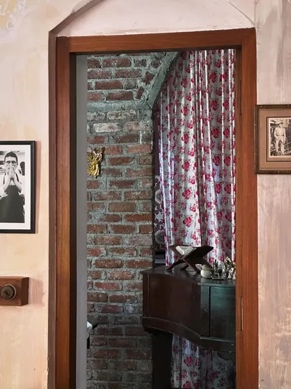 A peek through a doorway reveals layers of texture and pattern. The exposed brick wall, floral curtain, and antique furniture create a rich visual story. I love discovering these different angles each time I visit.