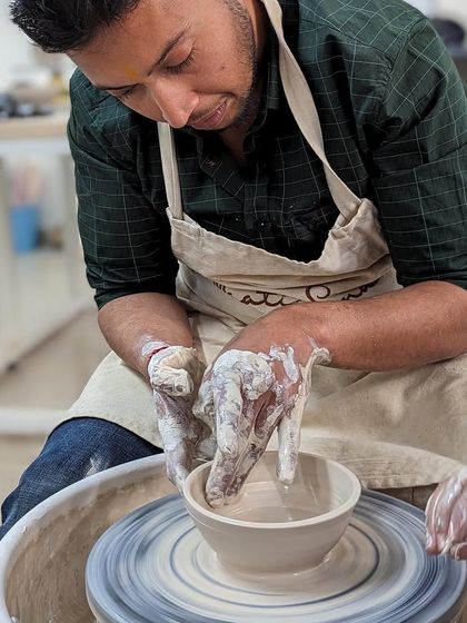 A student focuses on shaping a bowl during a Valentine's workshop, a perfect activity for creative couples.