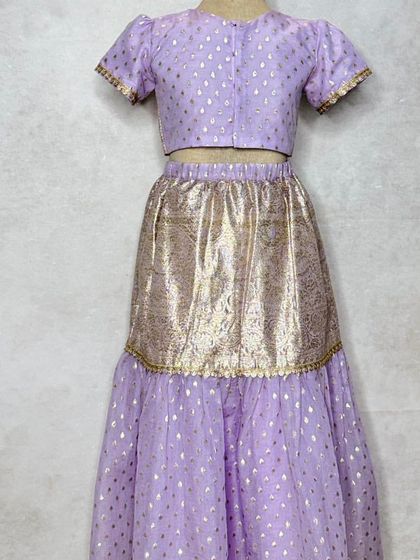 The back view of the lavender lehenga set, showing the simple choli that sits underneath the jacket.