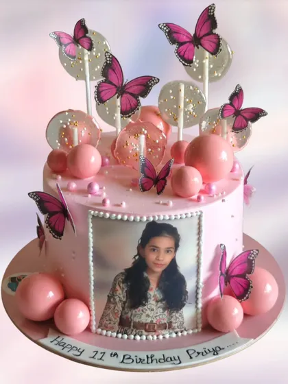 A photo cake for an 11th birthday, decorated with pink butterflies and lollipops. It's a sweet and personal way to celebrate.