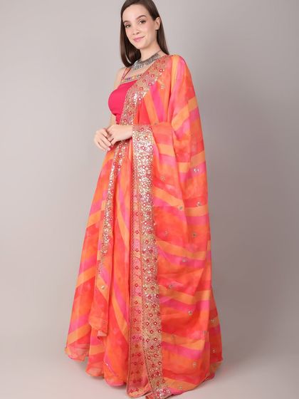 A side view of the orange and pink lehenga, emphasizing the elegant drape of the sequined dupatta.