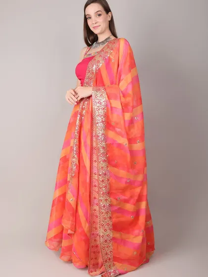 A side profile of the orange lehenga set, showing how the dupatta can be draped gracefully over the shoulder.