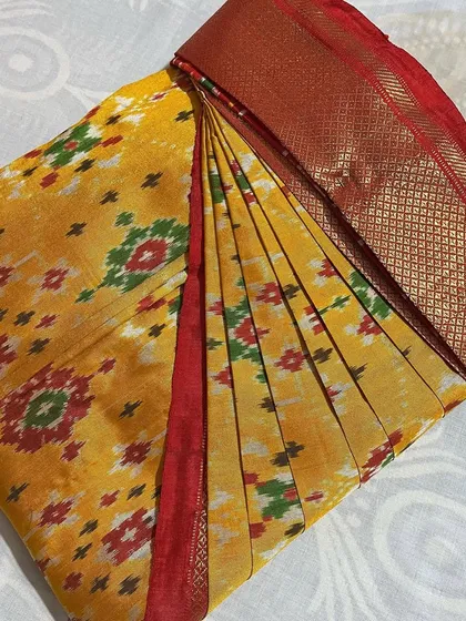A beautiful yellow Pochampally Ikat saree with a red border, folded to preserve its unique pattern.
